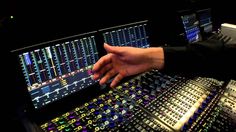 a person's hand on the control panel of a sound mixing console in a recording studio