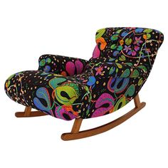 an upholstered rocking chair is decorated with bright colors and paisley designs on black fabric