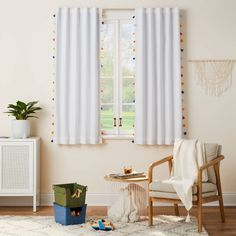 a living room with a chair, table and two windows covered in polka dot curtains