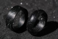 two black rings sitting next to each other on top of a table with water droplets