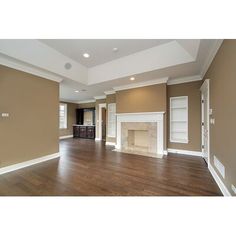 an empty living room with hard wood floors and white trim on the fireplace mantel