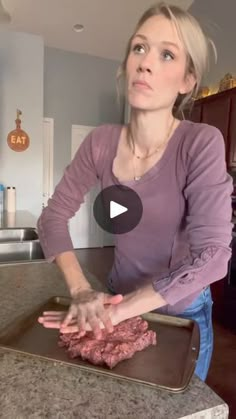 a woman standing in front of a pan with raw meat on it