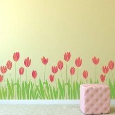 there is a pink stool in front of a wall with red tulips on it