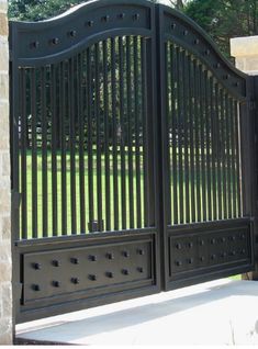 an iron gate in front of a brick wall and stone pillars with decorative designs on the sides