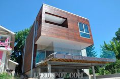 a modern house with wood and glass on the top floor, surrounded by concrete blocks