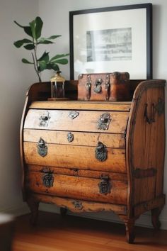 an old wooden chest sitting on top of a hard wood floor next to a potted plant