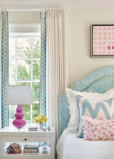 a bedroom with blue and white bedding, pink lamps and pictures on the wall