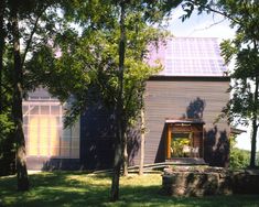 the house is surrounded by trees and has a solar panel on it's roof