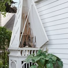 a white gazebo sitting on the side of a house next to potted plants