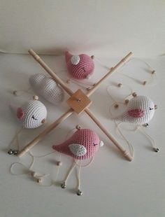 four crocheted birds sitting next to each other on a white surface with knitting needles