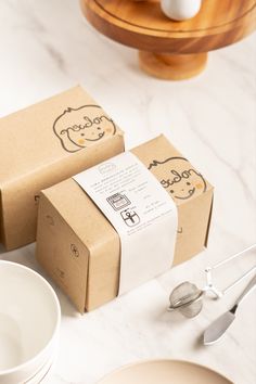 two boxes sitting on top of a table next to white plates and utensils