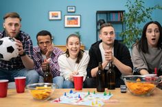 a group of people sitting around a table with drinks and soccer balls in front of them