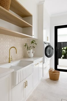 a white kitchen with open shelving and a washing machine in the corner next to it