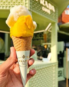 a hand holding an ice cream cone with yellow topping