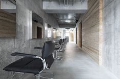 an empty room with chairs and mirrors on the wall, in front of a concrete wall