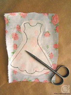 a pair of scissors sitting on top of a piece of fabric next to a dress