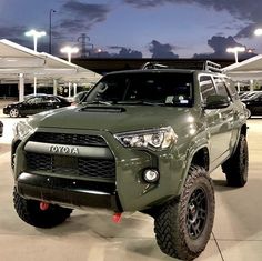 the front end of a green toyota truck parked in a parking lot with other cars