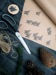 scissors, pine cones and other crafting supplies laid out on a table with wrapping paper