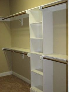 an empty walk in closet with white shelving and tan carpeted flooring on the walls