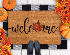 a welcome mat with fall leaves and pumpkins around it