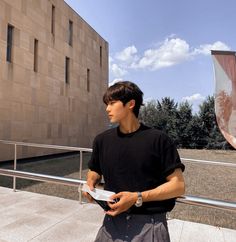 a young man is holding something in his hand while standing on the side of a building