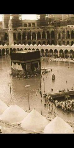 an old photo of people standing in the water near a large building that is surrounded by snow