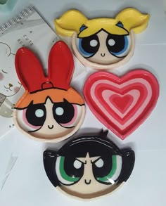 three decorated cookies with cartoon faces on them