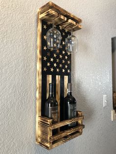 an american flag made out of wine bottles on a wooden shelf with two glasses hanging from it