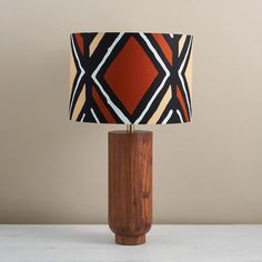 a wooden table lamp with a black, orange and white lampshade on it