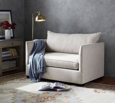 a living room with a couch, lamp and rug on the floor in front of it