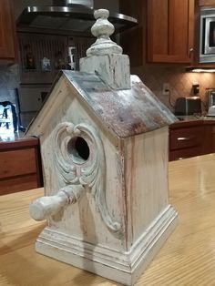 a white birdhouse sitting on top of a wooden table