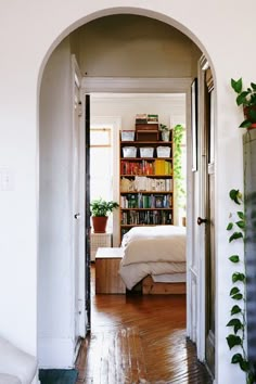 an archway leading to a bedroom with a bed and bookshelf