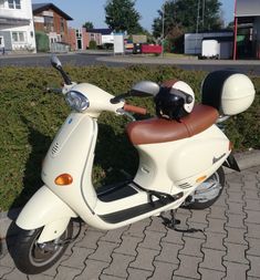 a scooter is parked on the sidewalk near some bushes