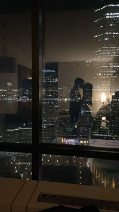 two people standing on top of a building at night with city lights in the background