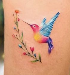 a colorful hummingbird with flowers on its back side ribcage, tattoo design