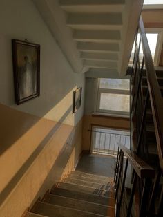 stairs leading up to the second floor in an old building with framed pictures on the wall