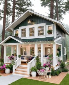 a green and white house with flowers on the porch