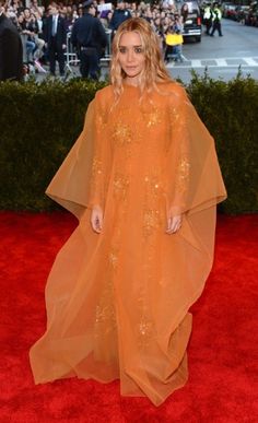 a woman in an orange dress standing on a red carpet