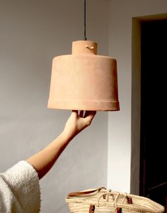 a person holding a light in their hand with a basket on the floor next to it