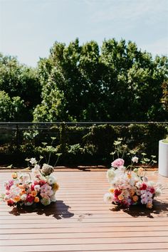 two vases filled with flowers sitting on top of a wooden floor