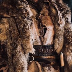 an animal fur coat with a leather belt and pen on the other side that is attached to it