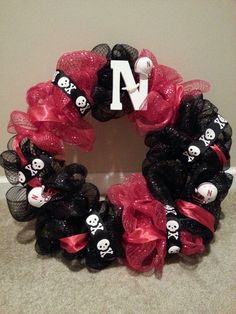 a wreath with skulls and bones on it is decorated in black mesh, red tulle