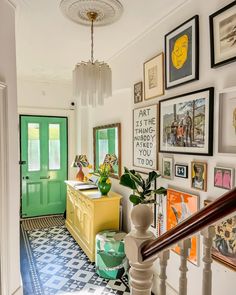 an entry way with pictures on the wall and green door in the center, next to a yellow chest of drawers