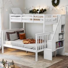 a white bunk bed sitting next to a christmas wreath on top of a wooden floor