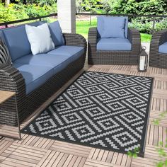 an outdoor patio with wicker furniture and blue cushions on the wooden decking area