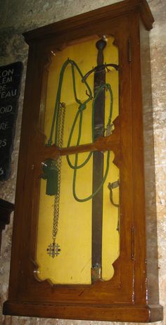 an old wooden clock with green cords attached to it