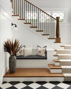 a white staircase with black and white checkered flooring next to a blue bench