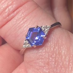 a woman's hand holding a blue ring with diamonds on it