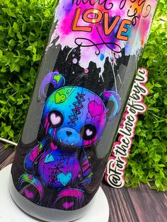 a colorful bear on a black and purple water bottle with the words love painted on it