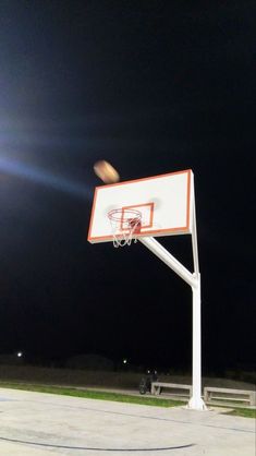 a basketball hoop in the middle of an empty court at night with lights shining on it